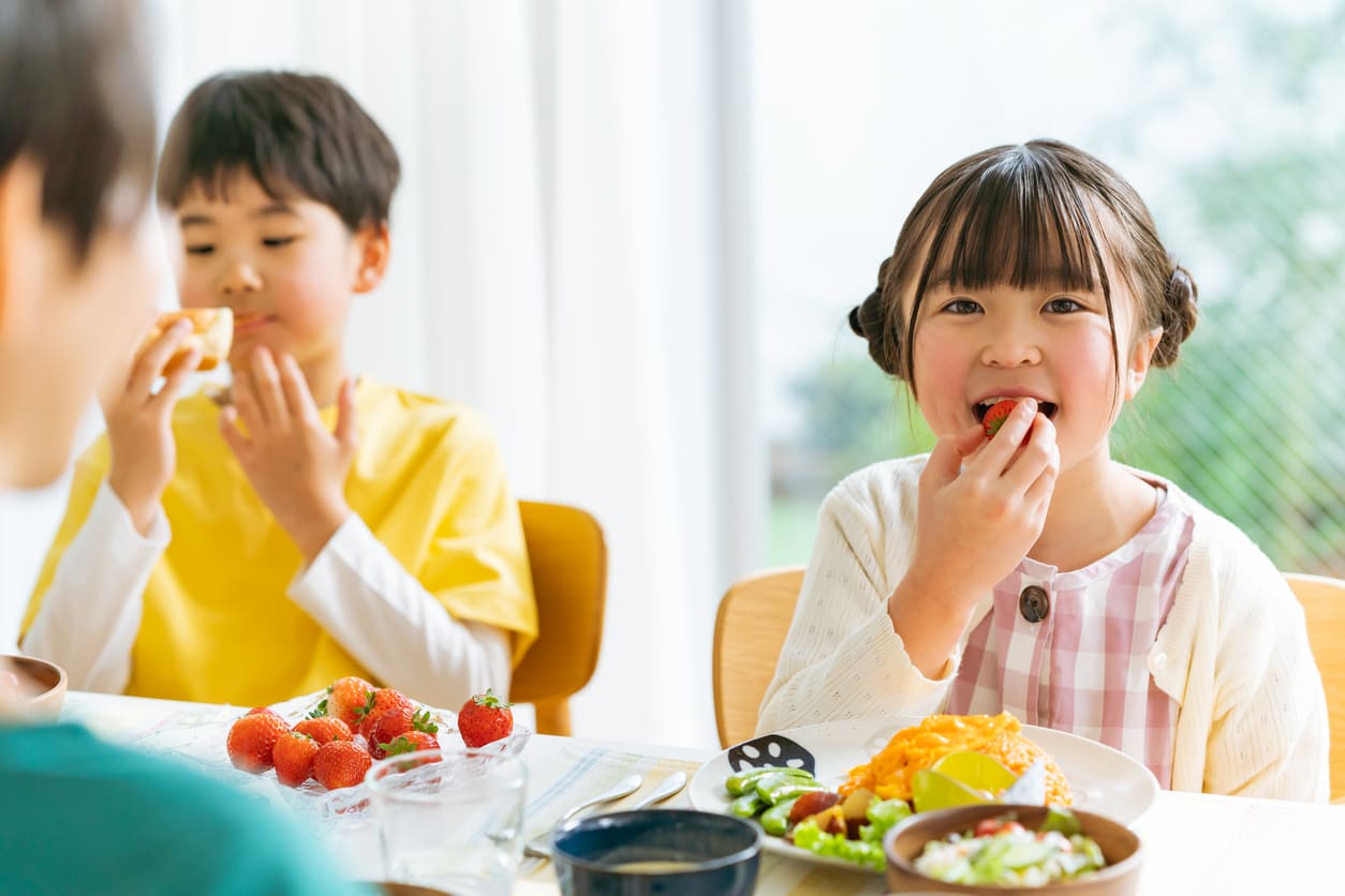 食卓で旬の野菜を食べる子どもたち